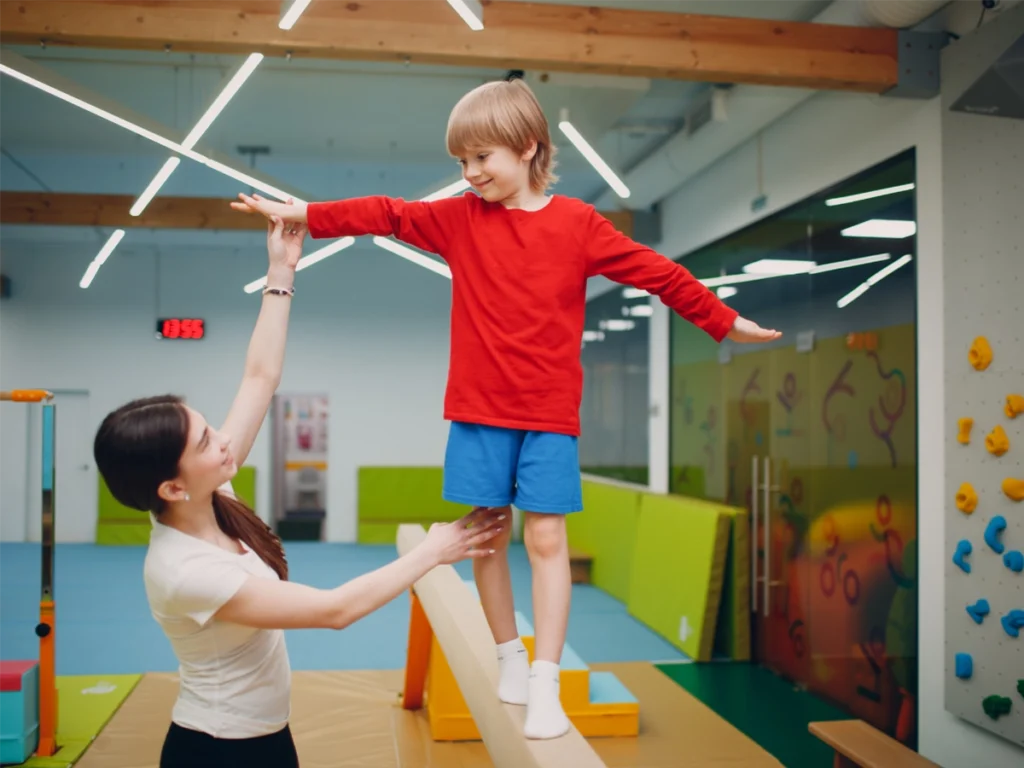 Gymnastics coach helps a boy keep his balance