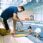 Swim coach instructs two students on technique