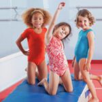 three young gymnasts play on a mat